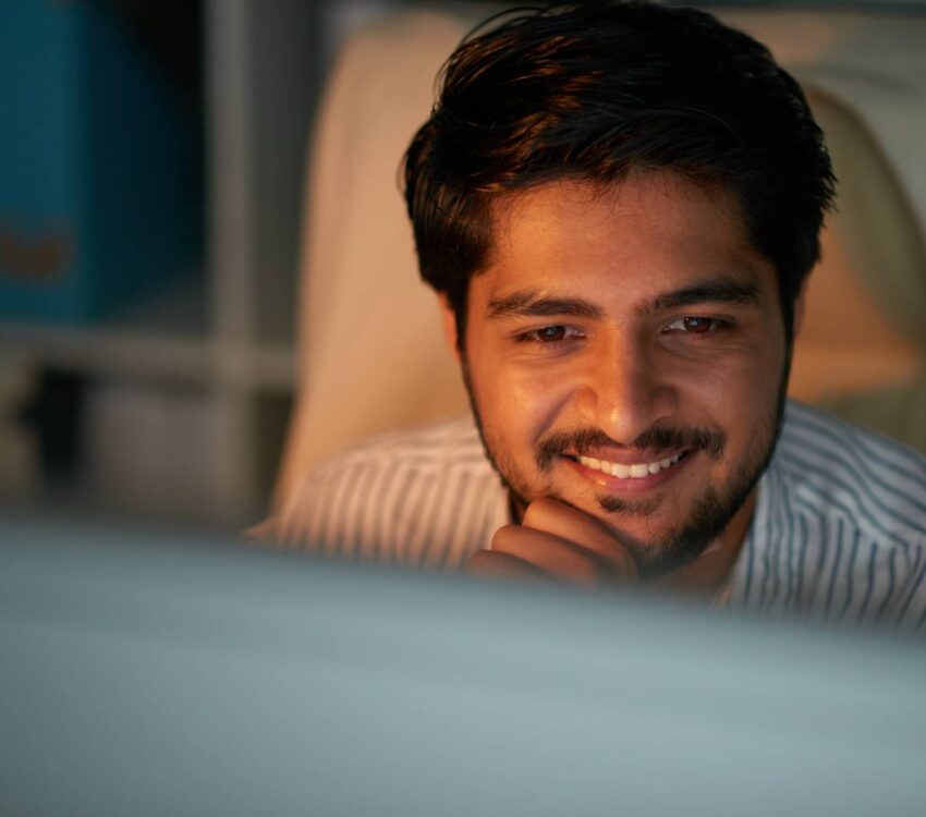 Smiling young Indian entrepreneur reading e-mails
